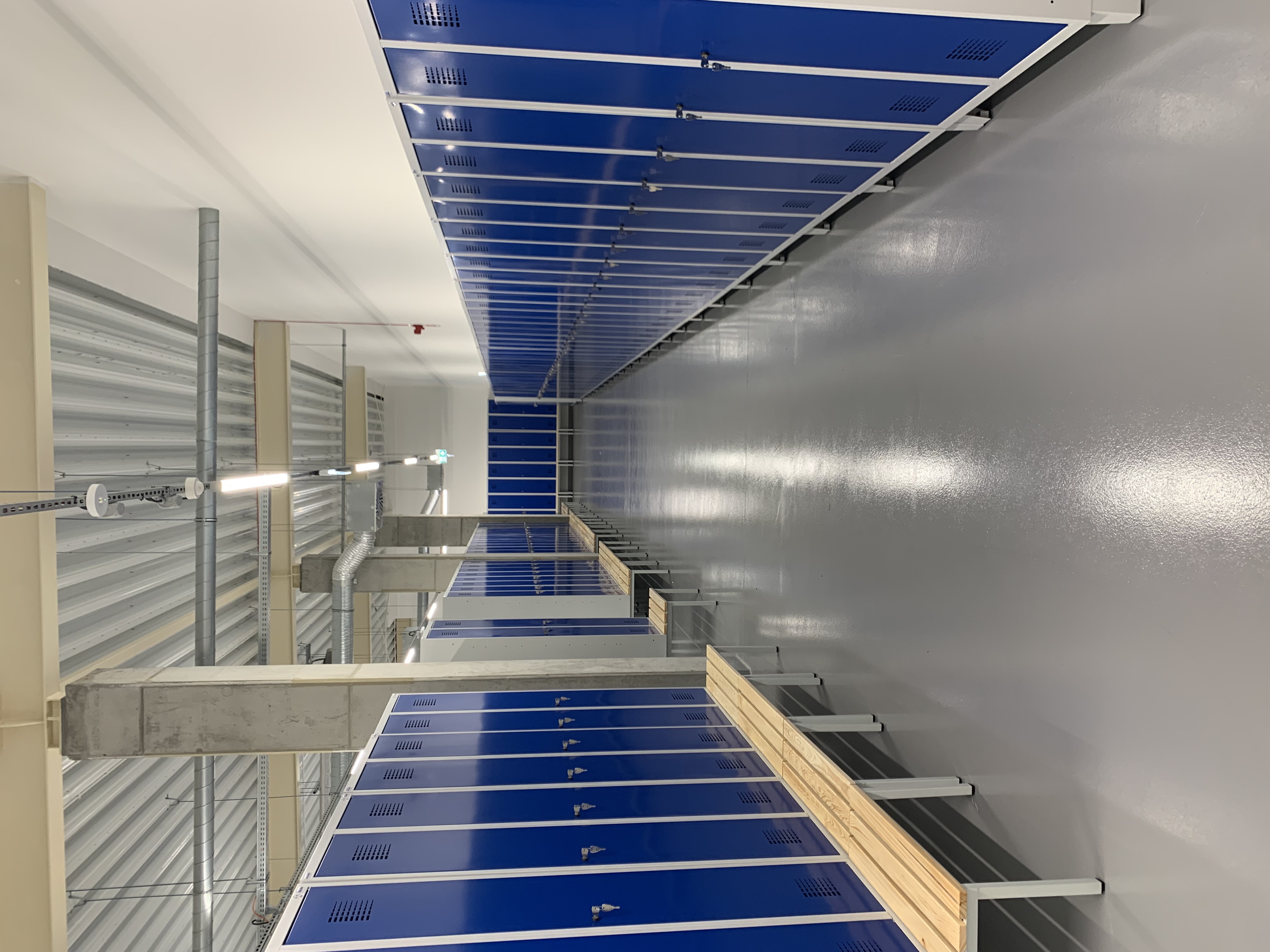 Metalowe szafy ubraniowe 80 cm z przegrodą na podstawie z siedziskiem oraz szafa na nóżkach, front RAL 5010 korpus RAL 7035 – realizacja Pozmebel Poznań